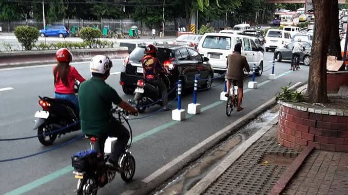 E-bike rider in a Metro Manila bike lane beside motorcycles and a cyclist